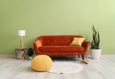 Kanepe, puf ve çiçek renkli duvarın yanında.