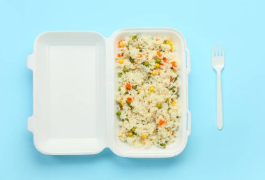 Konteynırda sebzeli lezzetli pirinç ve arka planda çatal.