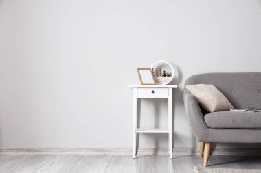 Çerçeveli beyaz masa ve ışık duvarının yanındaki kanepe.