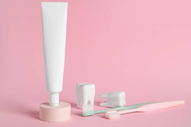 Arkaplanda diş macunu ve diş fırçası bulunan bir tüp.