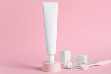 Arkaplanda diş macunu ve diş fırçası bulunan bir tüp.