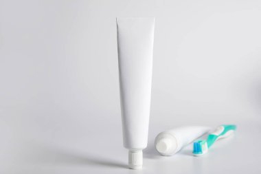 Işık arka planında diş macunu ve diş fırçası olan tüpler