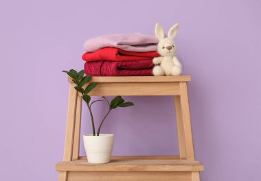 Çocuk süveteri, oyuncak tavşan ve renkli duvarın yanındaki saksı.