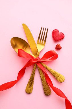 Pembe arka planda güzel çatal bıçak takımı ve kalpler.