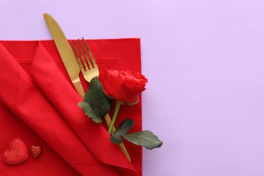 Güzel çatal bıçak takımı, gül çiçeği ve mor arka planda kalpler.
