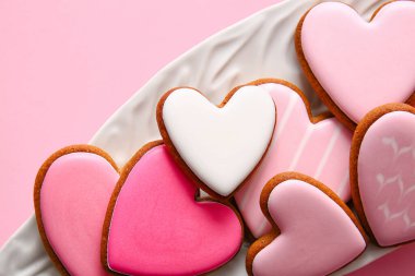 Pembe arka planda lezzetli kalp şekilli kurabiyeler, yakın plan.