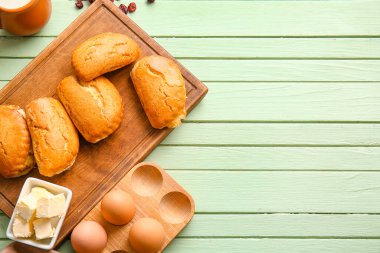 Yeşil ahşap arka planda süzme peynirli lezzetli sochniki tahtası, yakın plan.