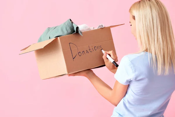 ボックスライティングの単語を持つ若い女性ピンクの背景に寄付 — ストック写真