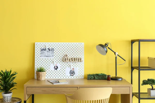 黄色の壁の背景にペグボードとスタイリッシュな職場 — ストック写真