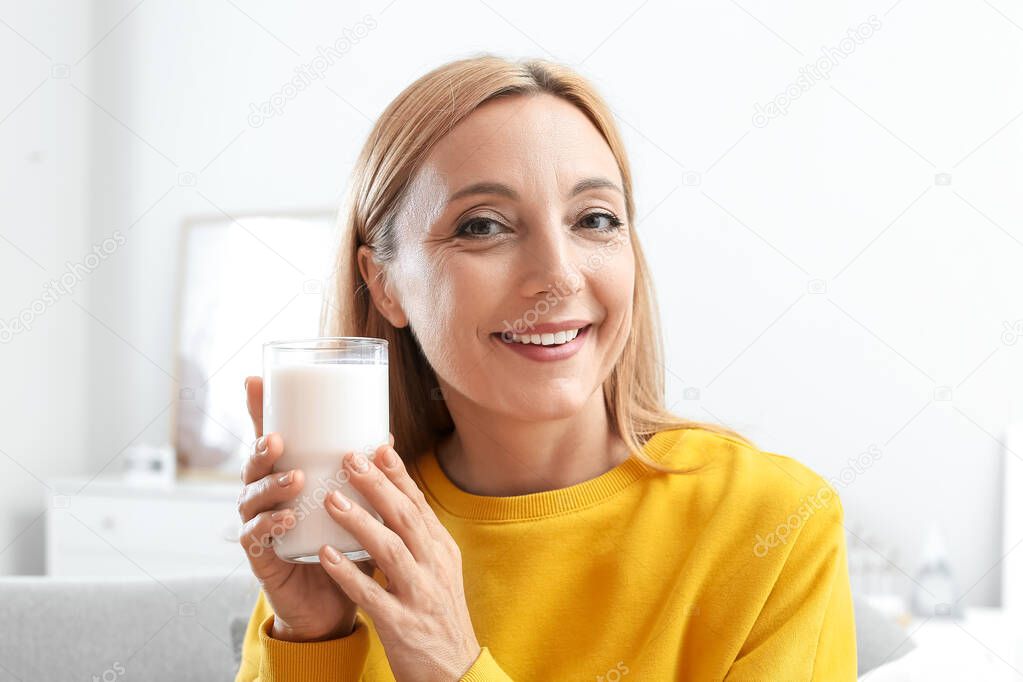Mature woman with glass of milk at home