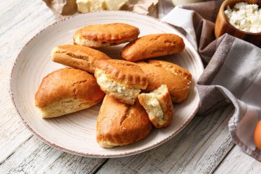 Beyaz ahşap arka planda süzme peynirli lezzetli sochniki tabağı.