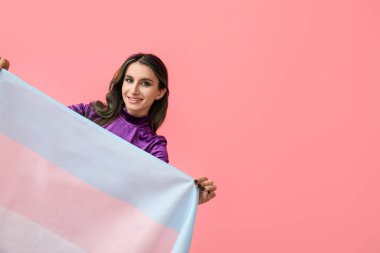 Renkli arka planda sıra dışı saçları ve transseksüel bayrağı olan güzel bir genç kadın.