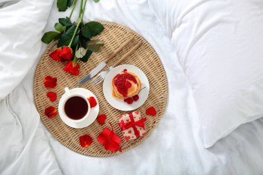 Lezzetli kahvaltı, güzel güller ve yumuşak yatakta sevgililer günü için hediyeler.