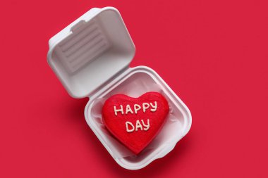 Kırmızı arka planda Sevgililer Günü için lezzetli bento keki olan plastik beslenme çantası.