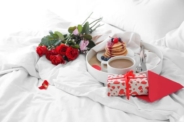 ベッドの上でバレンタインデーのためのおいしい朝食 バラの花束とギフトボックスでトレイ — ストック写真