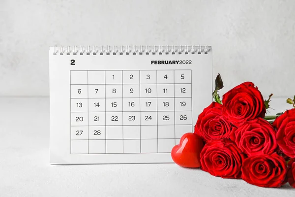 ライトの背景にテーブルの上に赤いバラとカレンダー バレンタインデーのお祝い — ストック写真