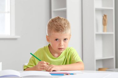 Evde kalemle çizen sevimli küçük çocuk.