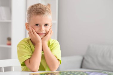 Evinde kitabı olan sevimli bir çocuk.