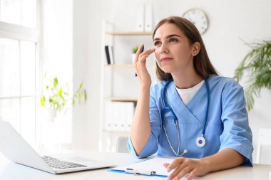 Klinikteki masada çalışan düşünceli kadın doktor.