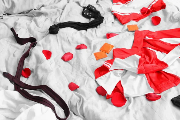 Erkek Kadın Giysileri Yatakta Gül Yapraklarıyla Kaplanmış Prezervatifler — Stok fotoğraf