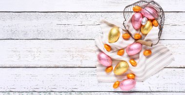 Beyaz ahşap zemin üzerinde çikolatalı Paskalya yumurtaları ve metin için yeri olan sepet.