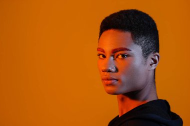 Renkli arka planda sıra dışı kaşları olan şık bir genç.