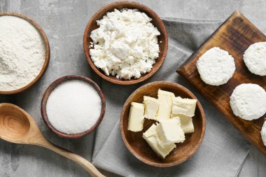 Gri arka planda krep hazırlamak için süzme peynir ve malzemelerle dolu bir kase.