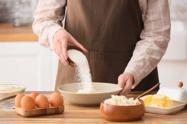 Mutfak masasında krep hazırlamak için süzme peynirli kaseye şeker koyan kadın, yakın plan.
