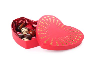 Kalp şeklinde bir kutu, beyaz arka planda izole edilmiş lezzetli çikolata şekerleri.