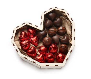 Kalp şeklinde bir kutu, beyaz arka planda izole edilmiş lezzetli çikolata şekerleri.