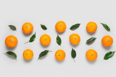Olgun mandalinalı kompozisyon ve beyaz arkaplanda yapraklar
