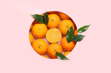 Olgun mandalinalı kompozisyon ve pembe arka planda yapraklar