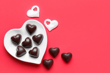 Kırmızı arka planda lezzetli kalp şekilli şeker tabağı.