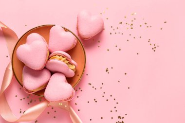 Lezzetli kalp şeklinde badem kurabiyesi ve pembe arka planda konfeti.