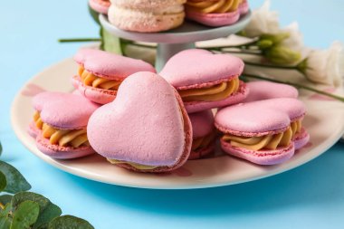 Mavi arka planda lezzetli kalp şeklinde badem kurabiyeleri olan tabak, yakın plan.