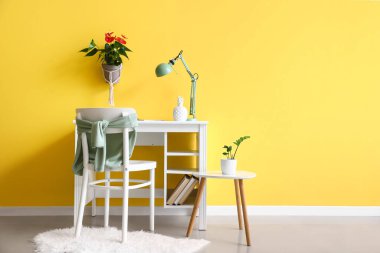 Modern iş yeri ve renkli duvarında güzel bir Anthurium çiçeği olan şık bir oda.