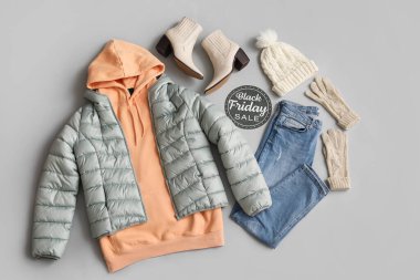 Siyah Cuma satışı yazılı kağıt, kalın kadın giysileri, aksesuarlar ve gri arka planda ayakkabılar