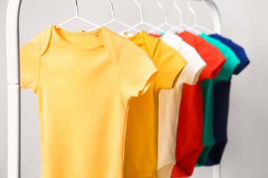 Işık duvarının yanında renkli bebek kıyafetleriyle dizilin, yakın plan.