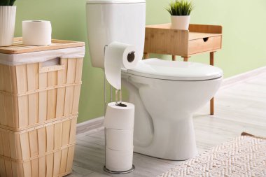 Yeşil duvarın yanında rulo kağıt ve klozet tutacağı