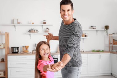 Mutlu adam ve küçük kızı mutfakta dans ediyorlar.