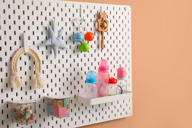 Bej duvarda asılı oyuncak ve şişelerle Peg tahtası, yakın plan.