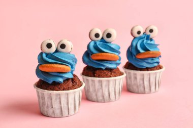 Cadılar Bayramı kutlaması için pembe arka planda lezzetli komik kekler.