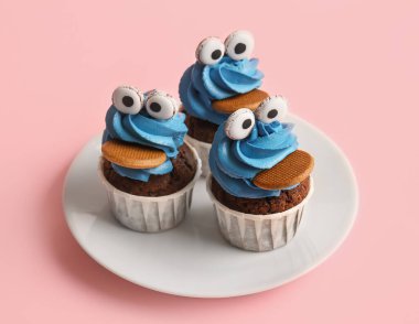 Pembe arka planda Cadılar Bayramı kutlaması için lezzetli komik keklerle dolu bir tabak.