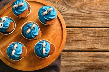 Cadılar Bayramı kutlaması için ahşap arka planda lezzetli komik keklerle dolu bir pano.