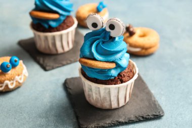 Cadılar Bayramı kutlaması için renkli arka planda lezzetli ve komik çöreklerle durun.