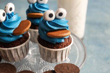 Cadılar Bayramı kutlaması için renkli arka planda lezzetli ve komik keklerle durun.