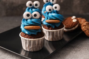 Cadılar Bayramı kutlaması için lezzetli komik keklerle dolu tabaklar, yakın plan.