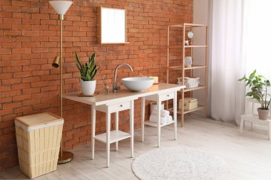 Lavabosu, aynası ve raf ünitesi olan şık bir banyo.