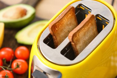 Mutfakta ekmek dilimleri olan sarı tost makinesi, yakın plan.
