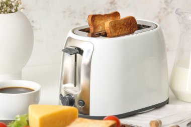 Mutfaktaki masada ekmek dilimleri olan beyaz ekmek kızartma makinesi.